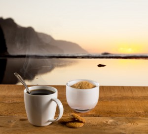 Cup of coffee on wooden table by ocean
