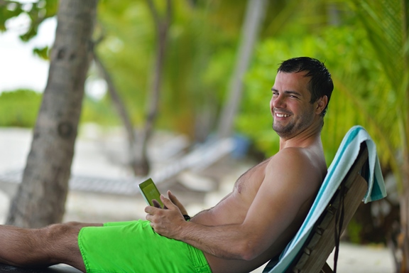 man ralaxing and use tablet at beach