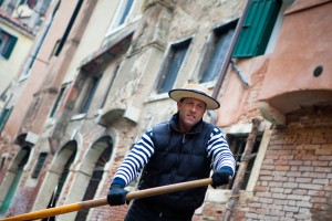 Gondolier navigates on the channel of Venice